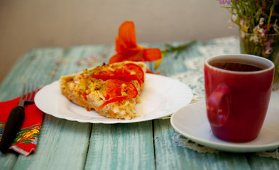 cup of tea on the table with bright orange flowers and a piece of vegetable pie