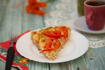 cup of tea on the table with bright orange flowers and a piece of vegetable pie
