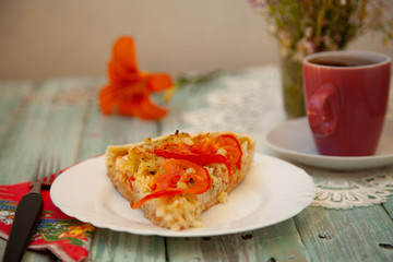 cup of tea on the table with bright orange flowers and a piece of vegetable pie
