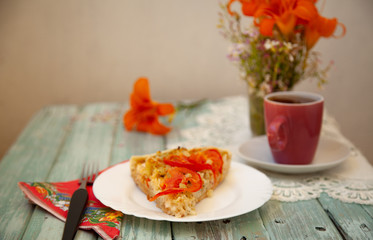 cup of tea on the table with bright orange flowers and a piece of vegetable pie