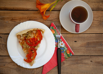vegetable pie with a cup of tea on a wooden table with orange flowers