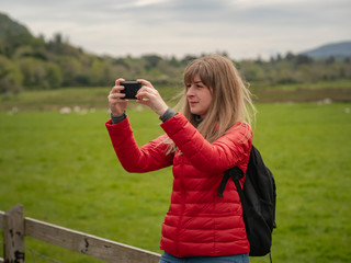 Young woman takes photos of the typical green landscape in Ireland - travel photography