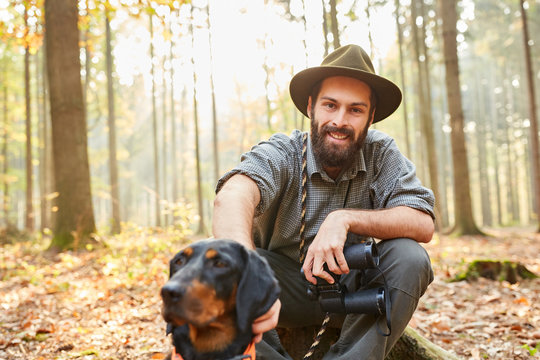 F&ouml;rster mit Jagdhund und Fernglas macht Pause