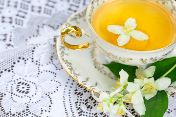 Jasmine tea in a porcelain Cup and jasmine flowers on lace table cloth, top view