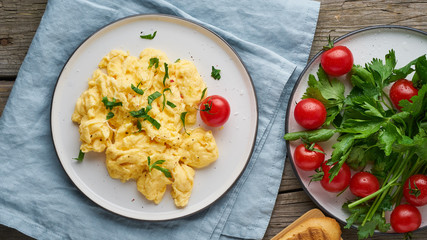 Scrambled eggs, omelette, long banner. Breakfast with pan-fried eggs, cup of tea, tomatoes on old wooden table