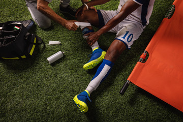 Soccer player injured knee during the game. Sport Doctors provide first aid to player on a...