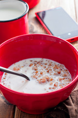 Breakfast with boiled buckwheat with milk in a red bowl, selective focus
