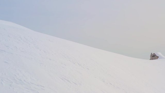 Man skier walking on snowy mountain while ski touring at winter day. Drone view tourist man splitboarding on snowy mountain peak. Winter sport and people activity. Aerial view