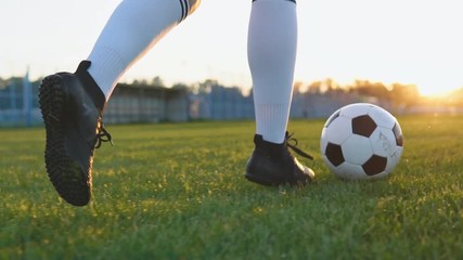 Close up of female football player running and kicking soccer ball at sunset in slow motion - Powered by Adobe