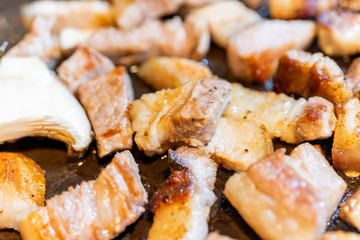 Pan-fried cooked black pork meal in Korea restaurant, fresh delicious korean food cuisine on iron plate with lettuce, close up, copy space, lifestyle