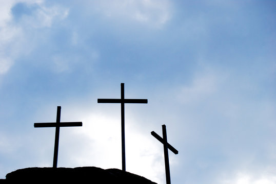 Three black Christian crosses with the cloudy sky
