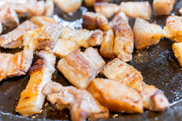 Pan-fried cooked black pork meal in Korea restaurant, fresh delicious korean food cuisine on iron plate with lettuce, close up, copy space, lifestyle