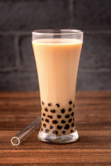 Delicious bubble milk tea with straw in drinking glass on wooden table background, concept of reduce plastic to go in Taiwan, close up, copy space