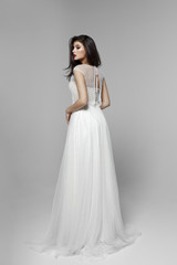Fototapeta na wymiar A side view of a gentle brunette model in classic white wedding dress, on white background.