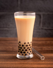 Delicious bubble milk tea with straw in drinking glass on wooden table background, concept of reduce plastic to go in Taiwan, close up, copy space