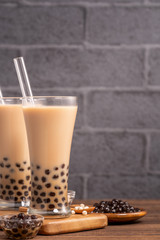 Delicious bubble milk tea with straw in drinking glass on wooden table background, concept of reduce plastic to go in Taiwan, close up, copy space
