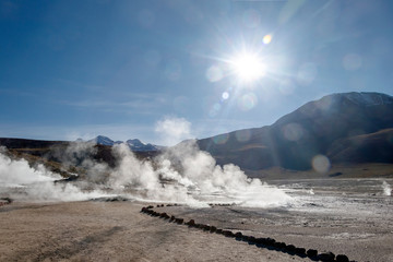 Bright rising sun above erupting Hot Geyser Of Steam in El Tatio Geysers field at early morning sunrise, Atacama desert, Chile