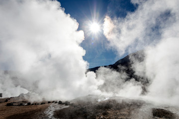 Bright rising sun above erupting Hot Geyser Of Steam in El Tatio Geysers field at early morning sunrise, Atacama desert, Chile