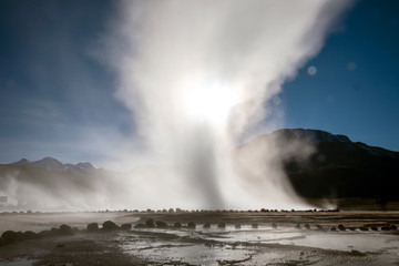 Atacama desert, Chile: Bright rising sun behind erupting Hot Geyser Of Steam in El Tatio Geysers...