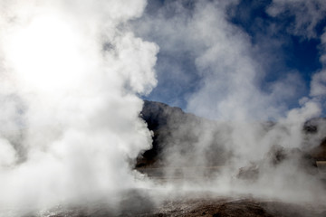 Atacama desert, Chile: Bright rising sun behind erupting Hot Geyser Of Steam in El Tatio Geysers field at early morning sunrise