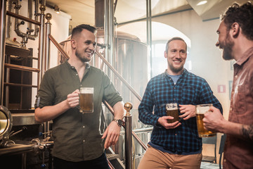 Three men tasting fresh beer in a brewery