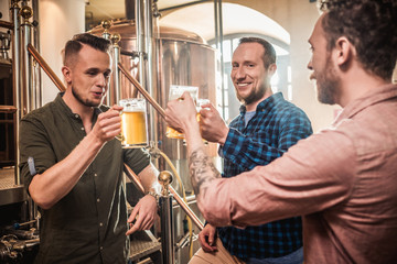 Three men tasting fresh beer in a brewery