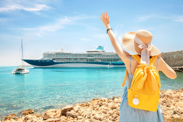 Happy woman tourist with backpack on a coastline, looking at the big cruise liner ship. Purchasing of tour and summer vacation concept - obrazy, fototapety, plakaty