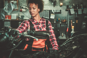 Fototapeta na wymiar African american woman mechanic repairing a motorcycle in a workshop