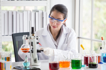 asian woman Scientist Research and Reaction woman pouring a liquid in a tube in Laboratory , science biology medicine chemistry concept