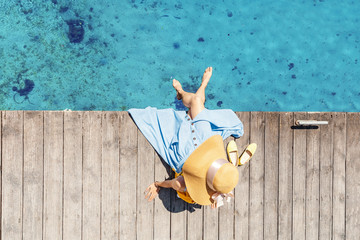The girl sits on the pier near the parked boats on the Mediterranean coast. Vacation and travel...
