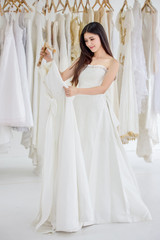 Fototapeta na wymiar Beauty portrait of young asian bride choosing wedding dress in wedding salon of fashion store ,luxury
