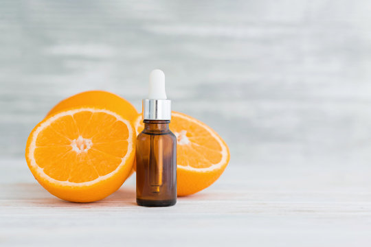Bottle with citrus natural orange essential oil on wooden background.