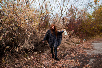 young redhead woman with white lamp in the hand in autumn park