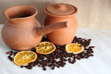 Turk and milk jug, made of clay dishes, a lot of roasted coffee bean and dried orange. composition, selective focus