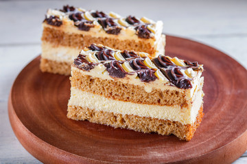 a piece of cake with milk and butter cream on a wooden kitchen board, white background..