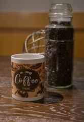 coffee time mug on a wooden table with coffee beans in a jar in the background