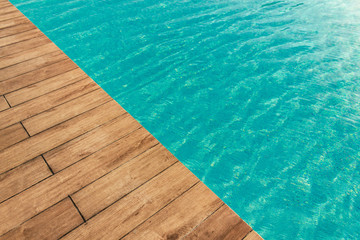Pool with wood open copyspace area.  Beautiful clean swimming pool with bright blue water.  Luxury relaxation and lifestyle travel concept.