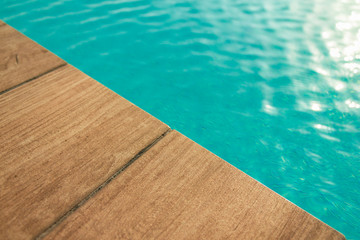 Pool with wood open copyspace area.  Beautiful clean swimming pool with bright blue water.  Luxury relaxation and lifestyle travel concept.