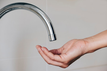 man waiting for water to come out of a tap