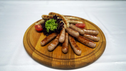 juicy sausages cooked on a grill, baked crust and served with fresh vegetables on the wood 