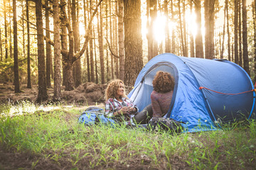 Trendy girls relaxing in the forest after an hiking day Couple of middle aged women discussing problems of menopause comforting each other.  Active lifestyle, old age, togetherness and healthy concept