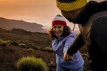 Giving a helping hand. Man helping female climber up a mountain. Smiling woman hiking with her...