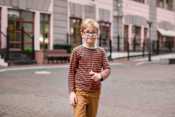 Strong, smart and funny little boy playing outdoors, wearing eyeglasses. Summer activities concept