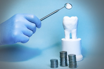 Closeup of a white healthy human tooth model and stacked coins. Financial Concept Dentist money concept. Whitening of tooth enamel