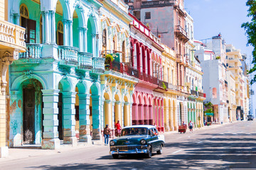 Fototapeta premium Chevrolet Bel air taxi driving through Havana in front of a colorful facade