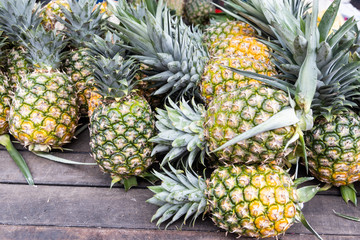 Heap of freshly harvested organic pineapple on wooden surface