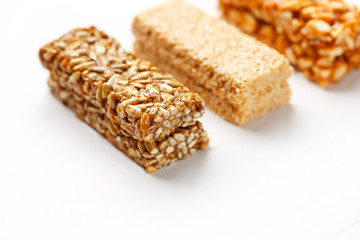 Grain granola bar with peanuts, sesame and seeds in a row on a white background. Top view Three assorted bars, isolate