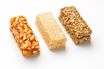 Grain granola bar with peanuts, sesame and seeds in a row on a white background. Top view Three assorted bars, isolate