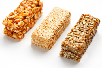 Grain granola bar with peanuts, sesame and seeds in a row on a white background. Top view Three assorted bars, isolate