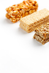 Grain granola bar with peanuts, sesame and seeds in a row on a white background. Top view Three assorted bars, isolate